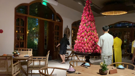 An indoor venue in Thao Dien, Saigon featuring a large, vibrant pink floral installation as the centerpiece. The space includes wooden furniture (tabl
