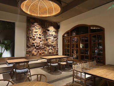 The image depicts the interior of a modern café or restaurant in Thao Dien, Saigon. It features wooden tables and chairs, a large decorative wooden wa