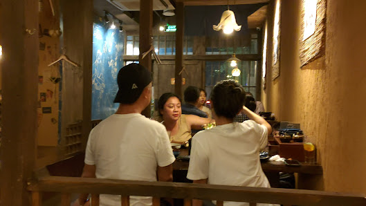 The image depicts an indoor setting of a restaurant or café in Thao Dien, Saigon. The interior has warm lighting and wooden decor with hanging light f