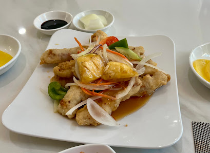 A plated dish consisting of what appears to be chicken stir-fried with vegetables such as carrots and green peppers on a white rectangular plate, acco