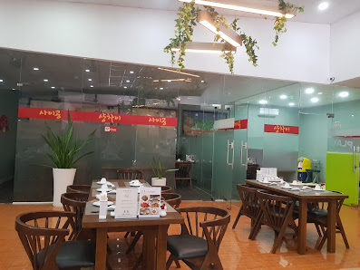 The image depicts the interior of a modern restaurant or café located in Thao Dien, Saigon. It features wooden tables and chairs arranged in a dining 