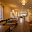 A blurry interior shot of a long, narrow room with wooden flooring, rows of tables and chairs, and soft lighting from ceiling fixtures. The space appe