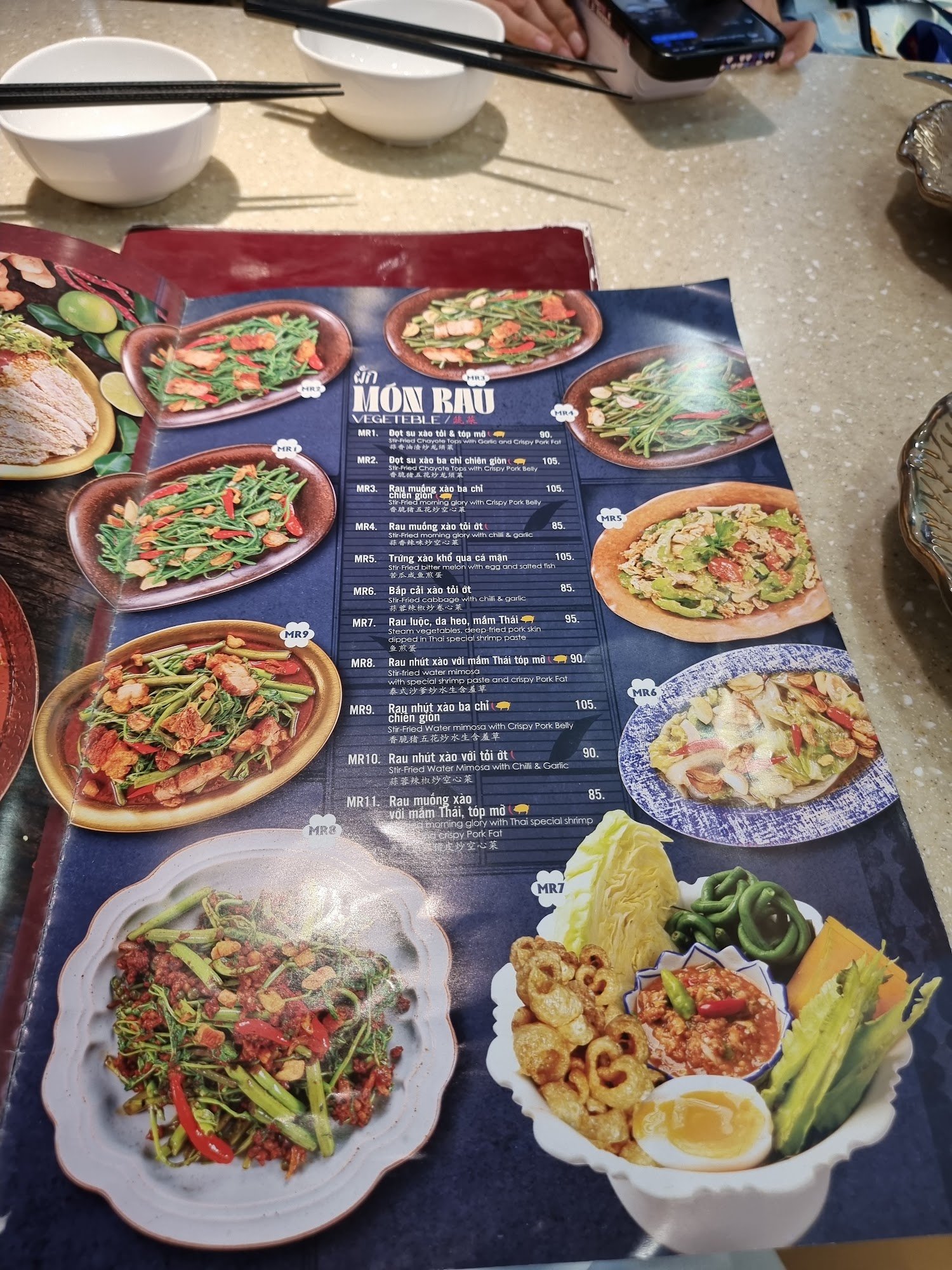 A menu from a Vietnamese restaurant in Thao Dien, Saigon featuring various dishes such as 'Món Bầu' and other traditional Vietnamese cuisine items.