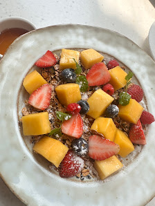 A plate of fruit topped granola and yogurt mix.