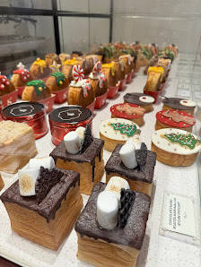 A display of various festive desserts and sweets arranged on a white surface in what appears to be a bakery or dessert shop.