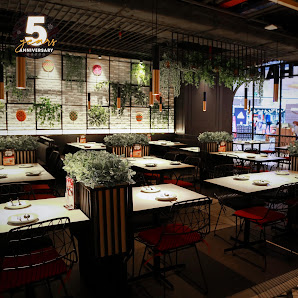 The image depicts an indoor dining area of a restaurant or cafe celebrating its fifth anniversary as indicated by the '5th Anniversary' sign on the wa