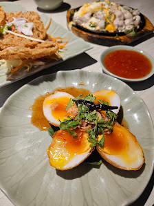 The image shows a plated dish consisting of what appears to be soft-boiled eggs with a runny yolk served on a white plate, garnished with green herbs 