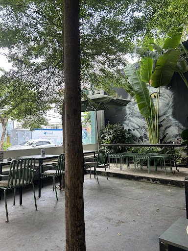 The image shows an outdoor seating area of a cafe or restaurant in Thao Dien, Saigon. The setting includes green chairs and tables arranged on what ap