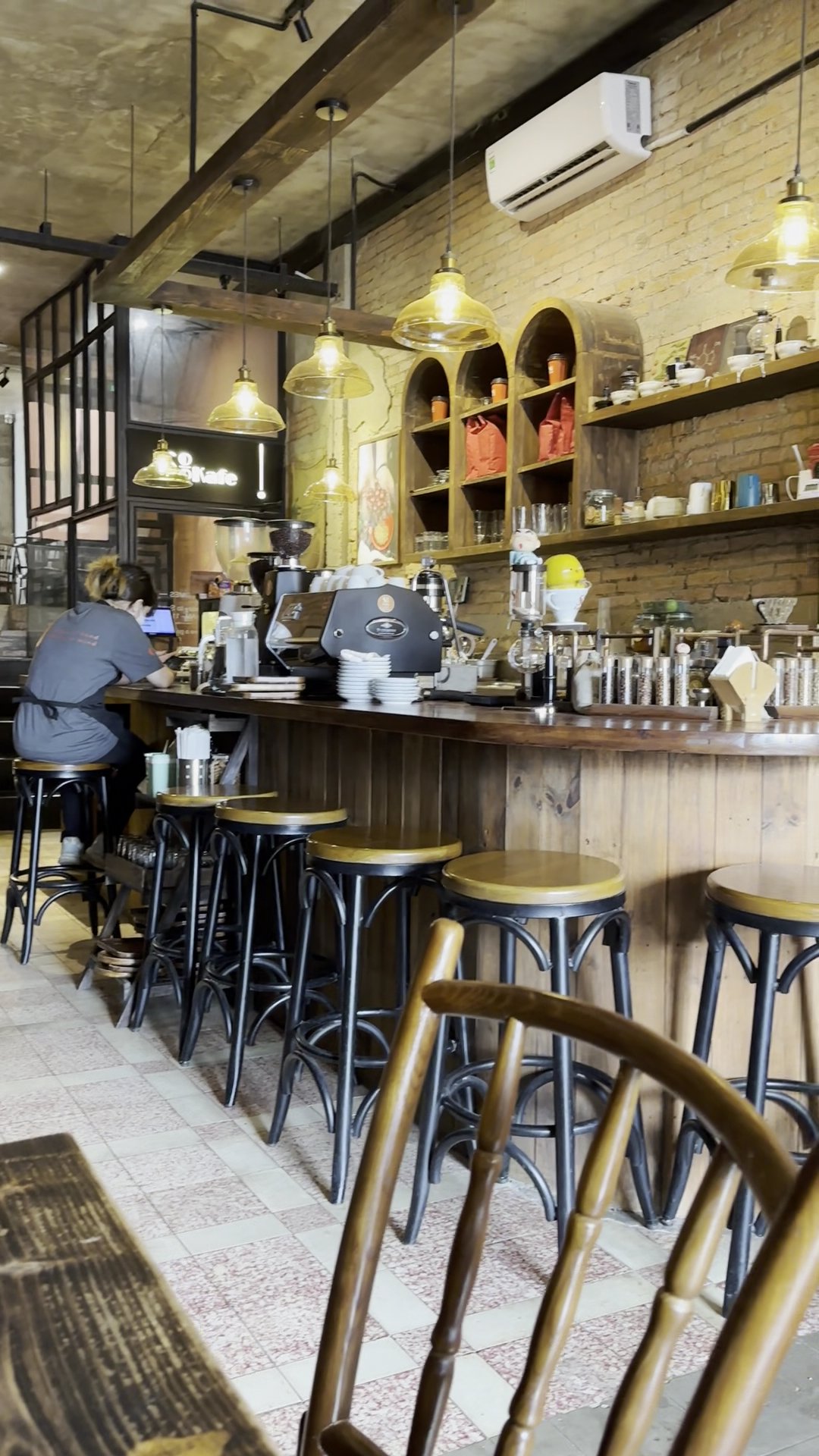 This image depicts an interior view of a coffee shop or café named 'Roast Cafe'. The setting includes wooden and brick walls, pendant lighting fixture