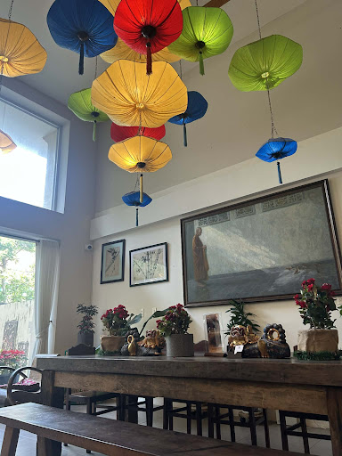 The image depicts an interior space that appears to be a cozy and well-decorated room with various colorful paper lanterns hanging from the ceiling, c