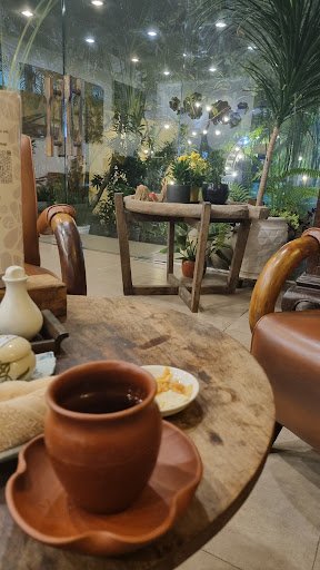 The image shows an indoor setting that appears cozy and inviting, featuring a wooden table with various items on it such as a ceramic cup of tea, plat