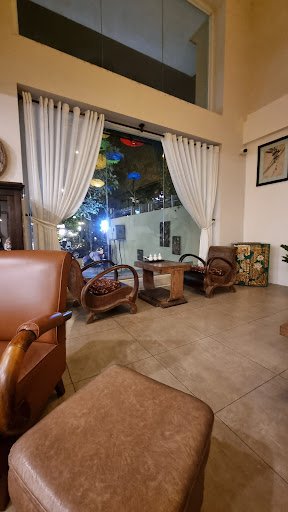 The image shows an interior space that appears to be a lounge or waiting area in Thao Dien, Saigon. The room features brown leather armchairs and otto