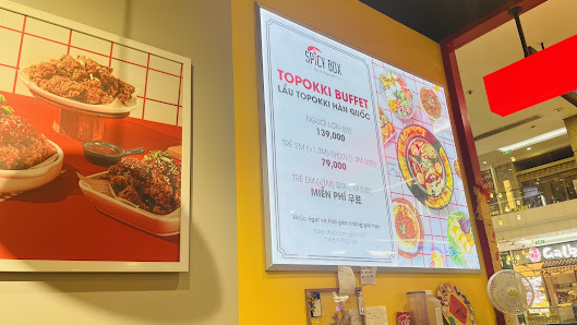 The image shows an interior view of a restaurant named 'Spicy Box' which features prominently displayed menus and food images on the walls, indicating