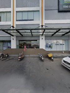 Exterior view of a commercial building in Thao Dien, Saigon. Features a covered entrance with a metal canopy, several parked motorbikes and a white ca