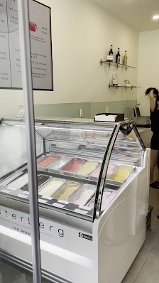 The image shows an interior view of a dessert shop or ice cream parlor featuring a display case with various frozen desserts, including what appears t