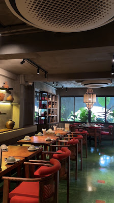 The image shows an interior view of a restaurant or dining establishment in Thao Dien, Saigon. The space features wooden tables and chairs with red cu