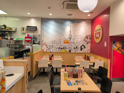 The image shows an interior view of a modern restaurant or cafe in Thao Dien, Saigon. The decor includes vibrant red and white walls with artwork depi