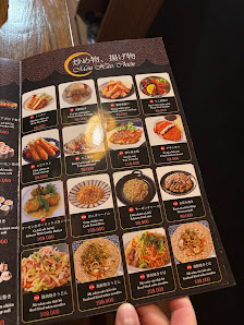 A person is holding a menu from Thao Dien, Saigon featuring various dishes such as noodles and stir-fries with prices listed in Vietnamese Dong.