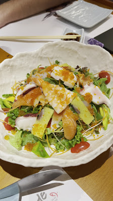 A plated dish consisting of a salad topped with what appears to be slices of fried egg and possibly some citrus segments like orange or mandarin, garn