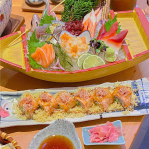 A plated dish of sushi and sashimi on a bed of rice garnished with various toppings such as fish roe, wasabi, pickled ginger, and green onions.