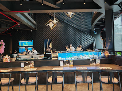 The image depicts the interior of a modern restaurant or café in Thao Dien, Saigon. It features a long counter with several staff members working behi