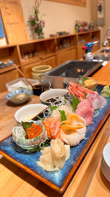 The image shows a well-lit interior of what appears to be an Asian restaurant with wooden decor and traditional elements such as bonsai trees on the c