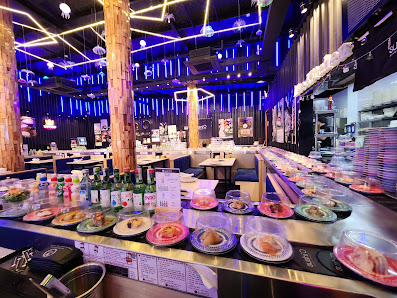 A modern restaurant interior in Thao Dien, Saigon, featuring a long counter with various dishes (plates of food, bowls, bottles), wooden pillars, blue