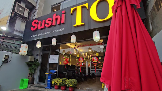 Exterior shot of Sushi TO restaurant in Thao Dien, Saigon. Features a black sign with 'Sushi' in red and 'TO' in yellow, accompanied by Vietnamese tex