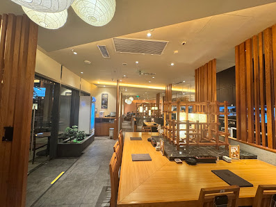 The image shows an interior view of a modern restaurant or cafe in Thao Dien, Saigon. The space features wooden elements and warm lighting, creating a