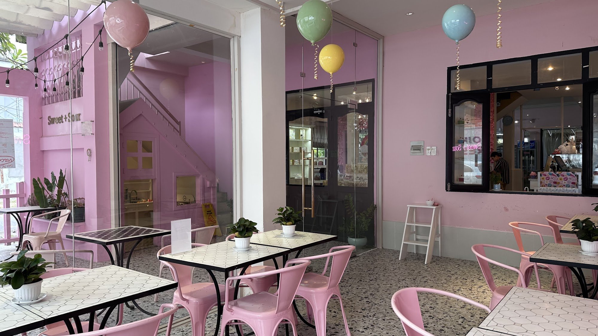 The image shows an interior view of a cafe named 'Sweet+ Sour' in Thao Dien, Saigon. The decor is vibrant with pink and purple tones dominating the sp