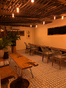 This image depicts an indoor space that appears cozy and warmly lit, featuring a rustic wooden ceiling with exposed beams, pendant lights hanging from