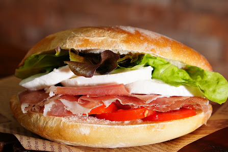 A close-up of a sandwich filled with lettuce, tomato slices, cheese, and sliced meat on a toasted bun.
