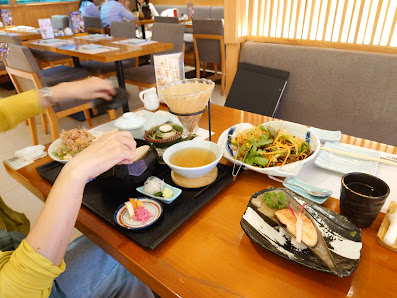 A dining table in a restaurant with multiple dishes including a bowl of noodles, a plate with seafood (such as shrimp), a bowl of soup, a glass of ice