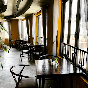 The image depicts the interior of a venue in Thao Dien, Saigon, featuring wooden tables and chairs arranged in a spacious layout. Large windows with y