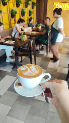 A coffee cup is held in the foreground of a busy cafe interior at Thao Dien, Saigon.