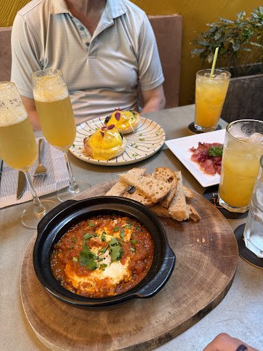 A dish that appears to be a type of baked or gratinated cheese with herbs on top, served in a black skillet.