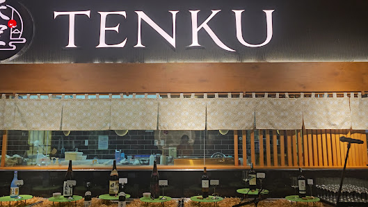 The image shows an interior view of a restaurant named 'TENKU'. The establishment appears modern with wooden and beige tones, featuring a bar area in