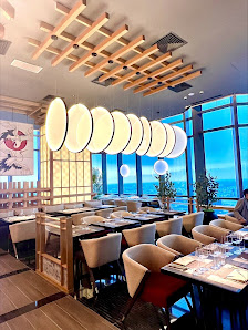 This image depicts an interior view of a modern restaurant featuring large windows that offer a scenic ocean view during the day.