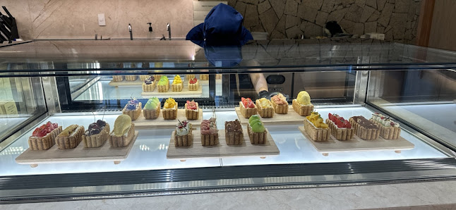 A glass display case in a café/restaurant in Thao Dien, Saigon, showcasing an assortment of pastries and desserts. The case contains multiple trays wi