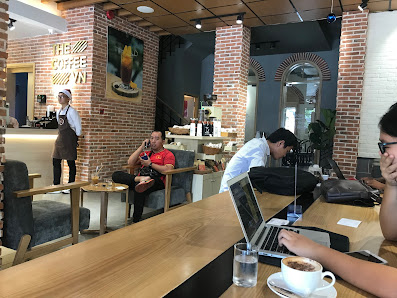 The image shows an interior view of a coffee shop named 'Hill Coffee,' which has exposed brick walls and modern decor elements such as framed artwork,