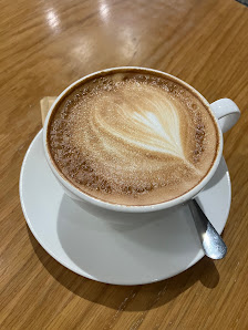 A cappuccino in a white cup and saucer on a wooden table.