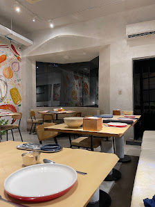 The image depicts the interior of a modern restaurant in Thao Dien, Saigon. It features several wooden tables with chairs, some set with plates, cutle