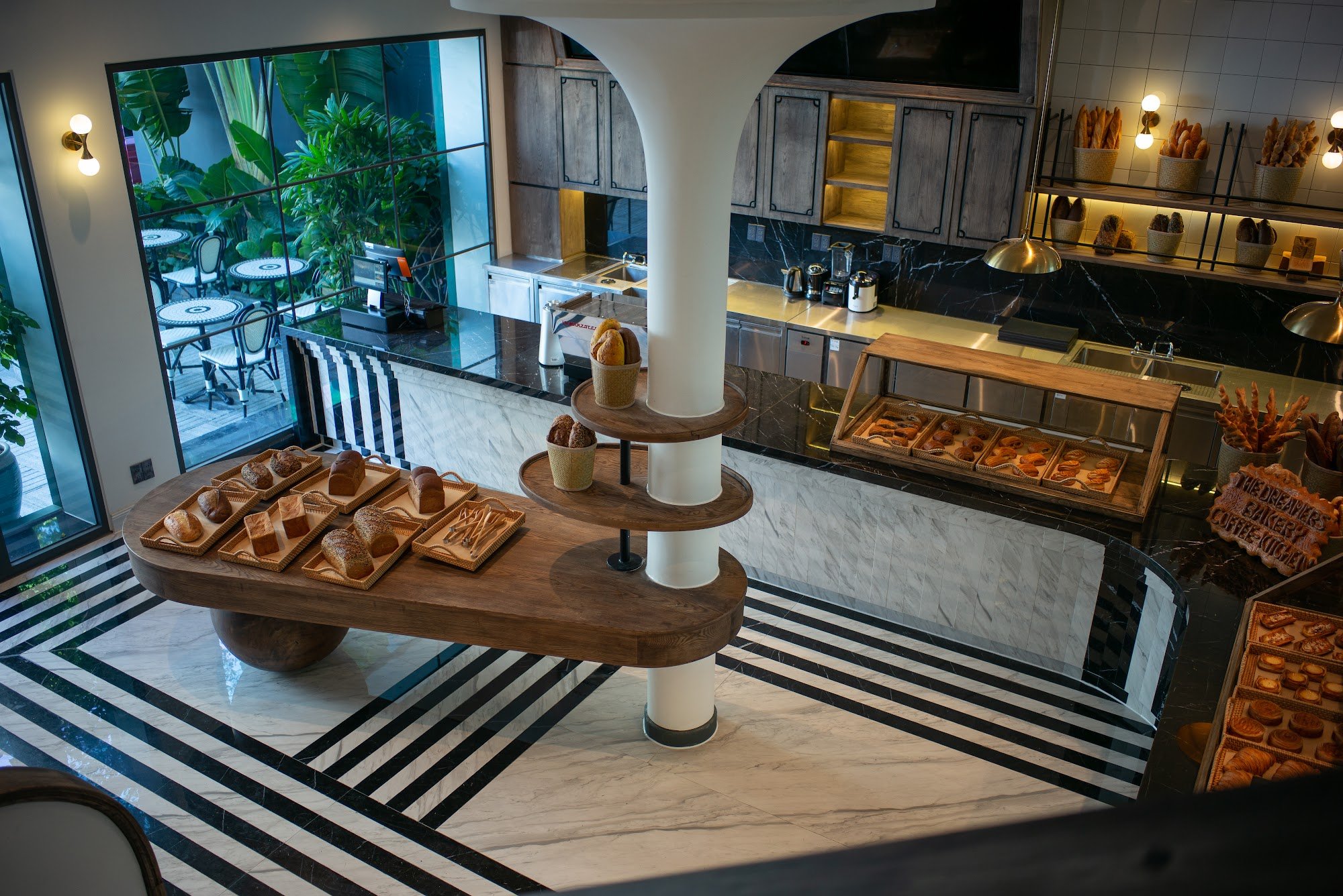 This image depicts an upscale interior of a bakery or café located in Thao Dien, Saigon. The space features modern design elements with dark wood acce