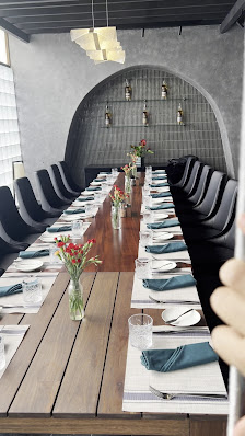 The image depicts a modern conference room or dining area in Thao Dien, Saigon with a long wooden table surrounded by black chairs and set for an even