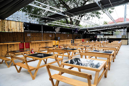 The image shows an outdoor seating area of a venue in Thao Dien, Saigon with wooden tables and benches arranged neatly under a semi-open structure cov