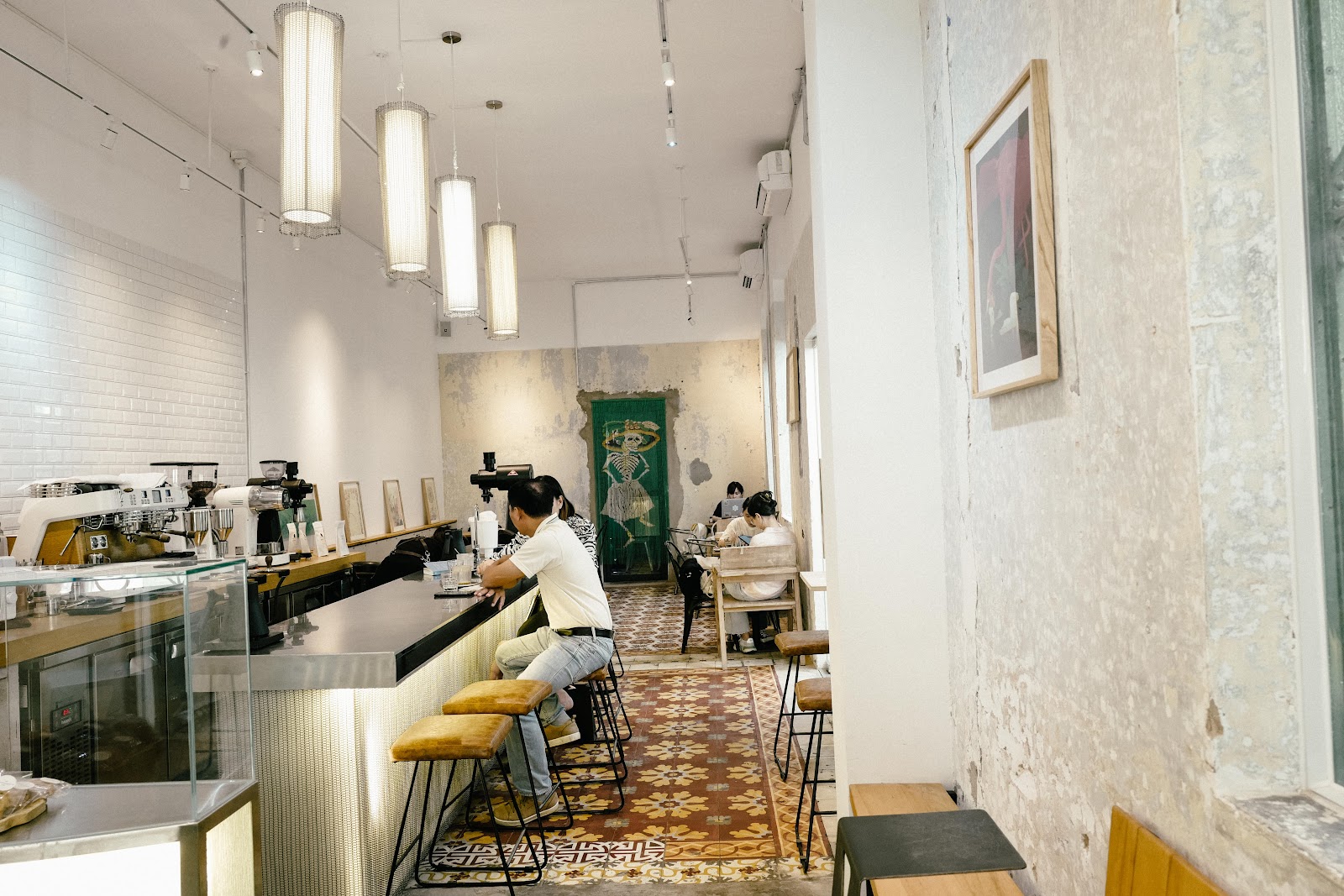 The image depicts an interior view of a modern coffee shop or café in Thao Dien, Saigon. The space features exposed brick walls with some areas showin