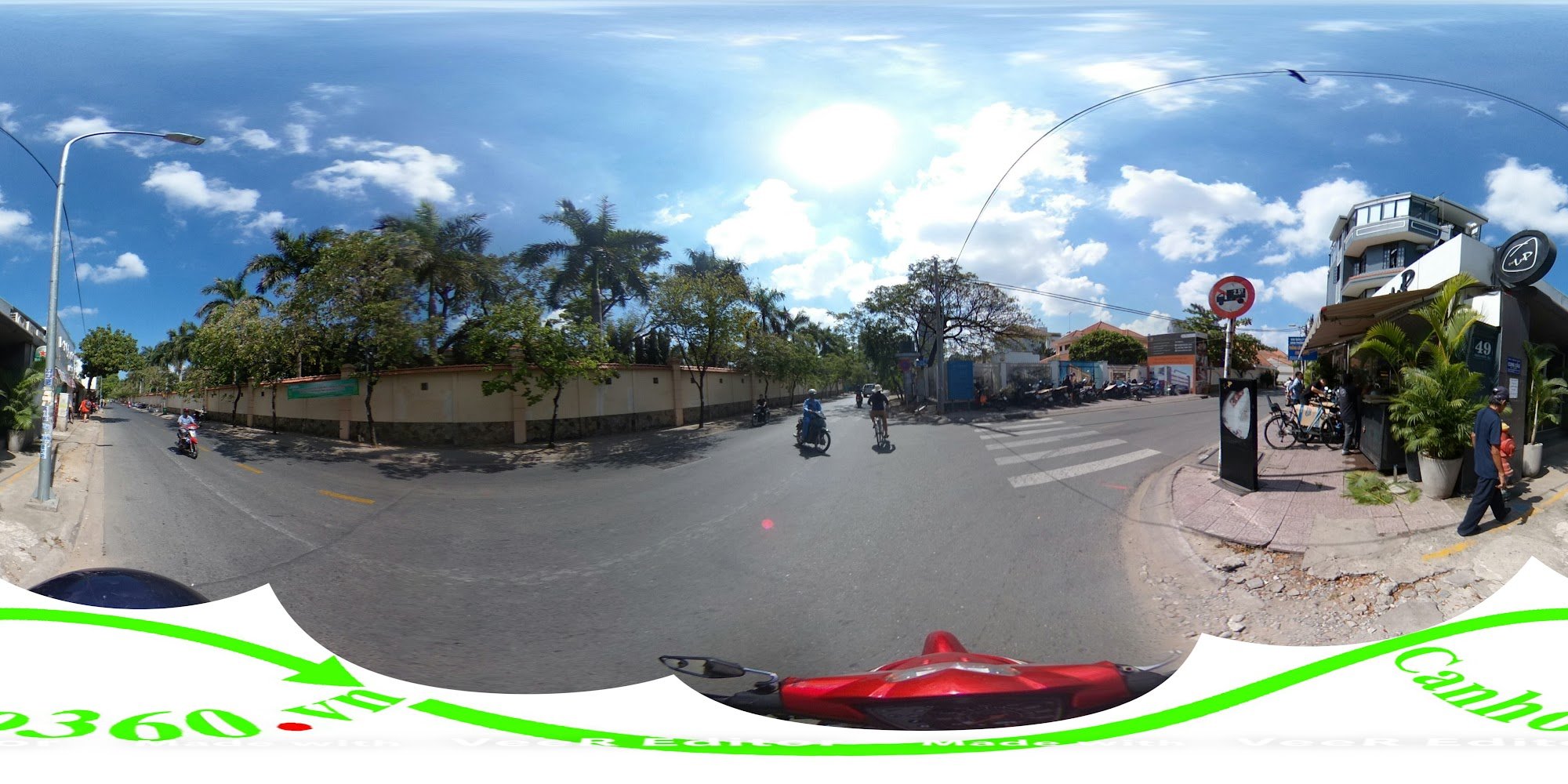 A panoramic 360-degree street view of Thao Dien, Saigon, showcasing a sunny urban scene with a red motorcycle in the foreground, palm trees lining a w