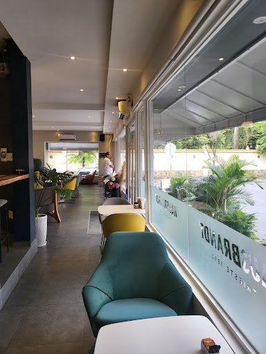 The image shows an interior view of a modern café or restaurant named 'BRAVO'. The space features contemporary design elements such as green upholster