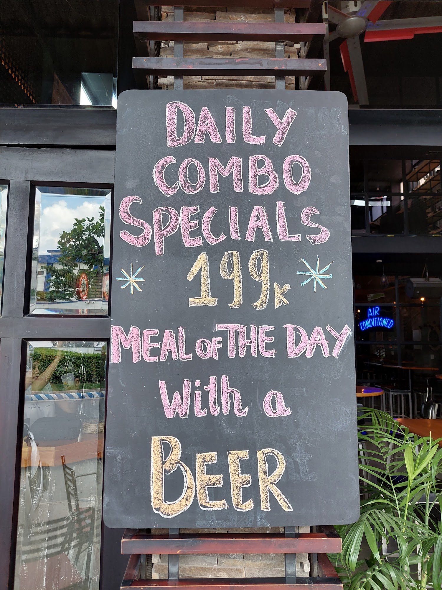 A chalkboard sign advertising daily combo specials and a meal of the day at Thao Dien, Saigon.