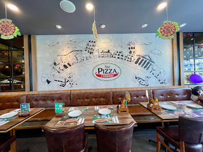 The interior of a restaurant featuring large murals on the wall depicting an Italian town and its landmarks with 'Mr. Pizza' branding prominently disp